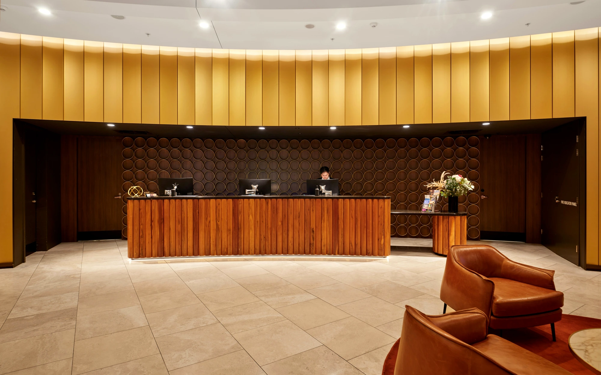 Reception counter wrapped in fluted wood and soft stone finishes